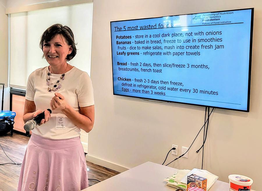 woman a pink skirt standing in front of a screen giving  a presentation
