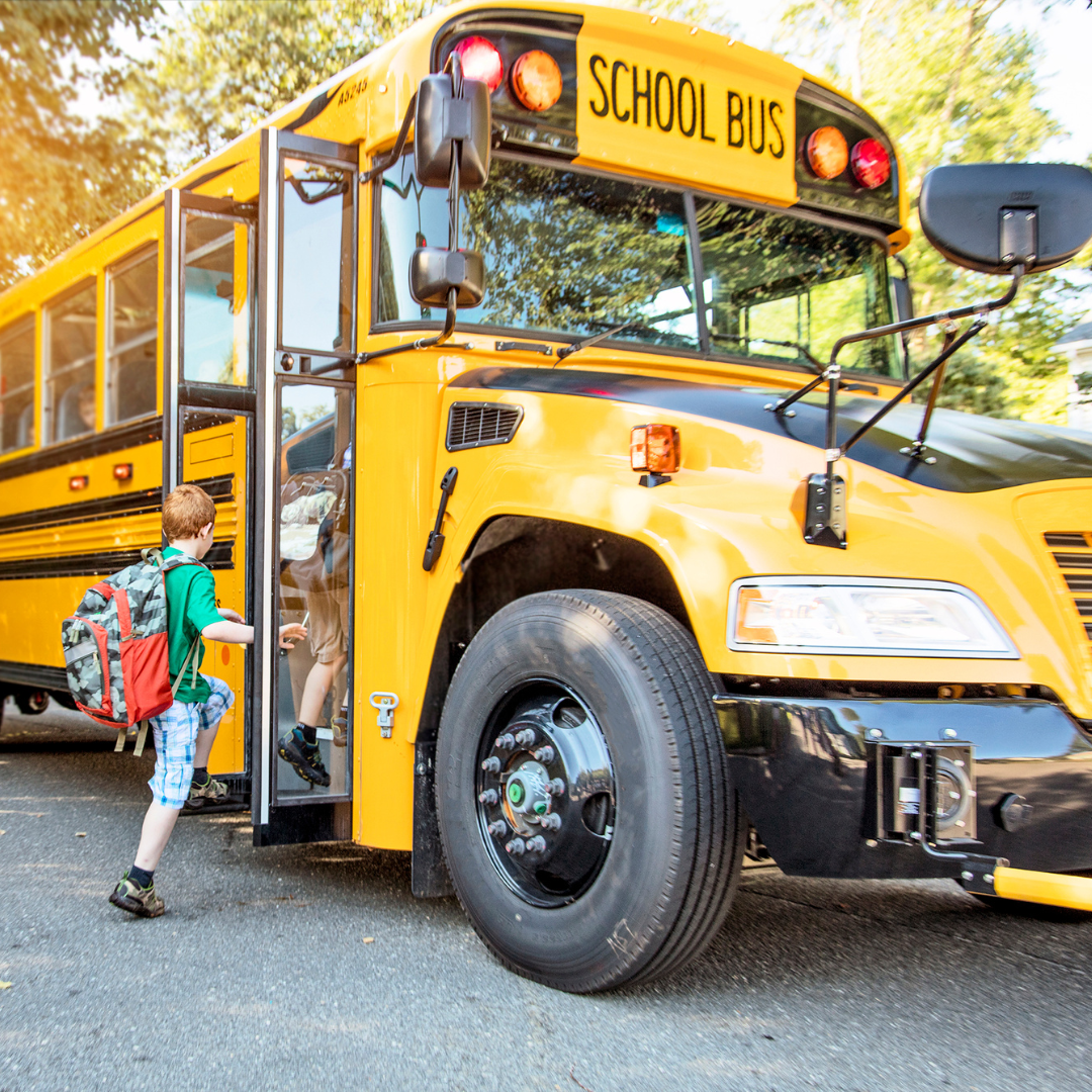 A child boards a yellow school bus.