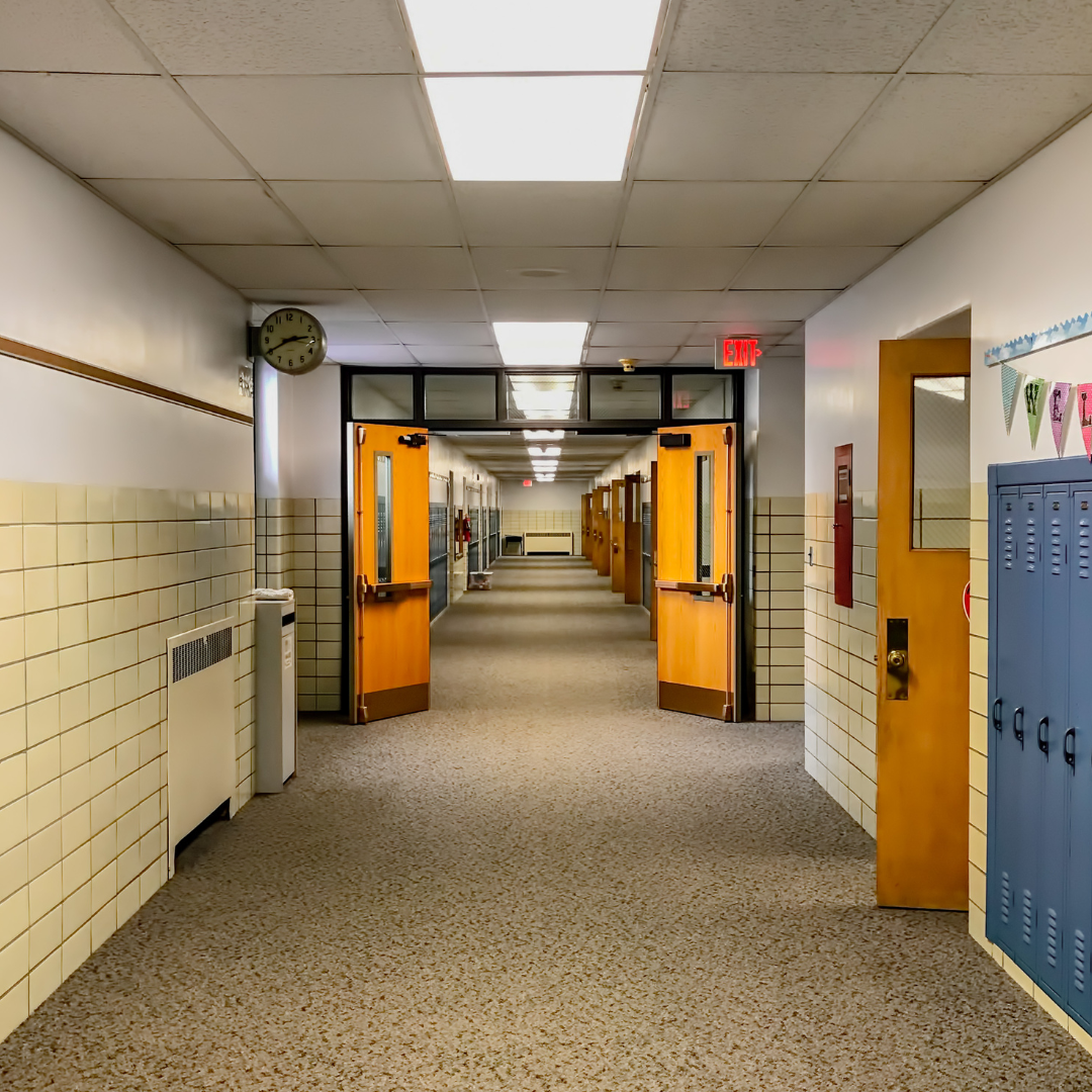 An empty elementary school hallway with doors and lockers.