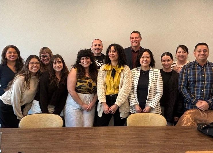 The California Civil Rights Department's Outreach and Education unit smile together during their planning retreat in Oakland.