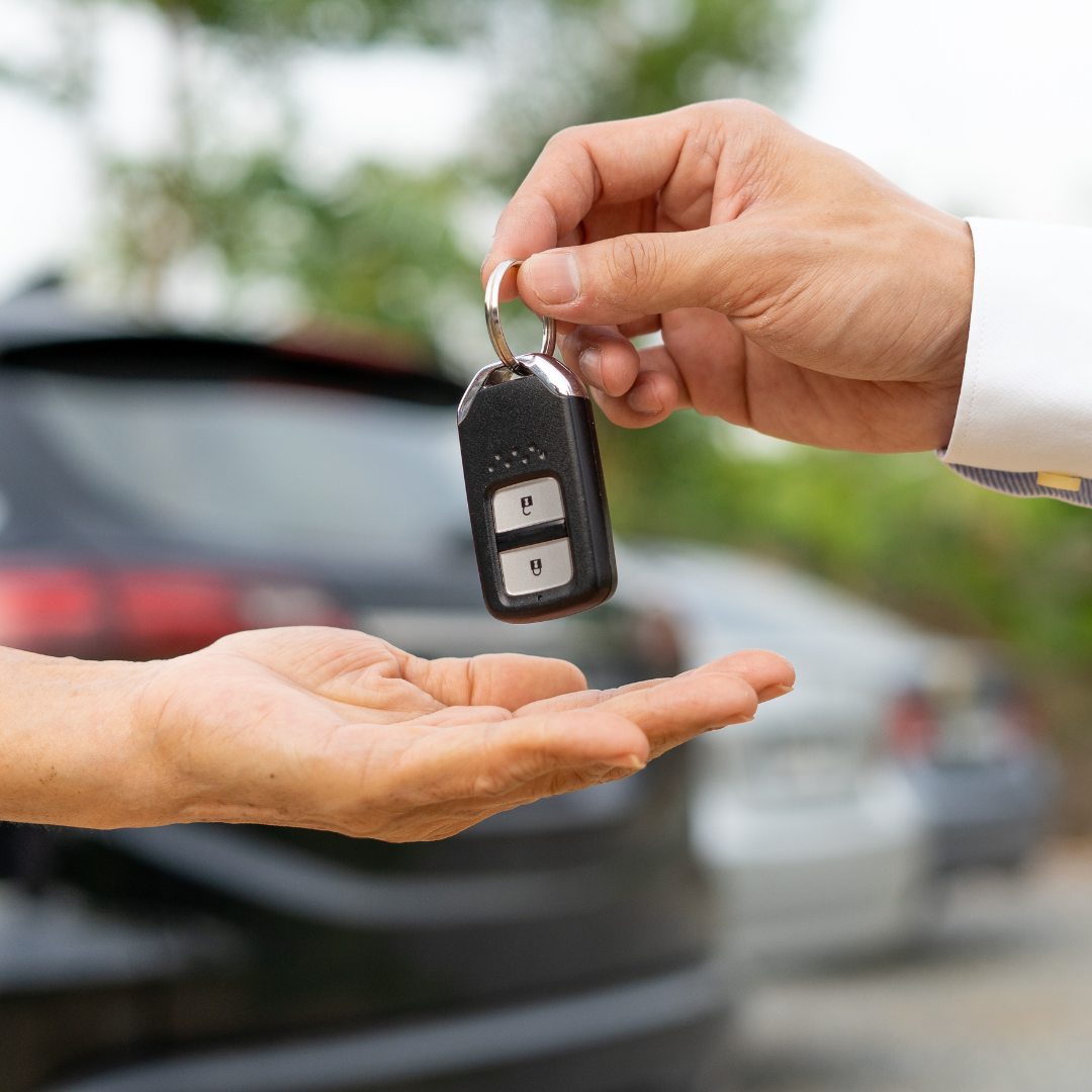 A car salesperson hands the keys to a new car to the customer.