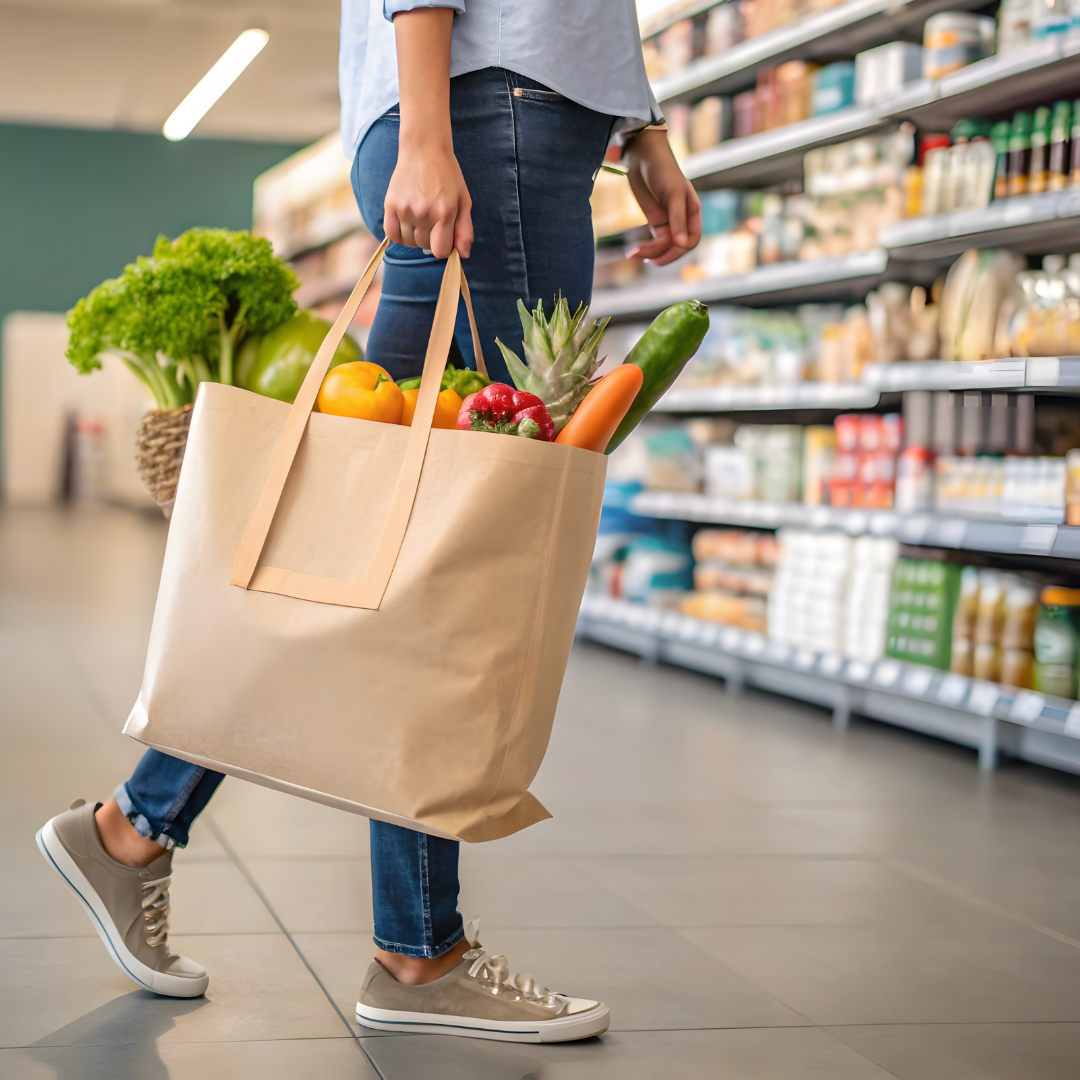 A woman holds a grocery bag full of produce inside a store.
