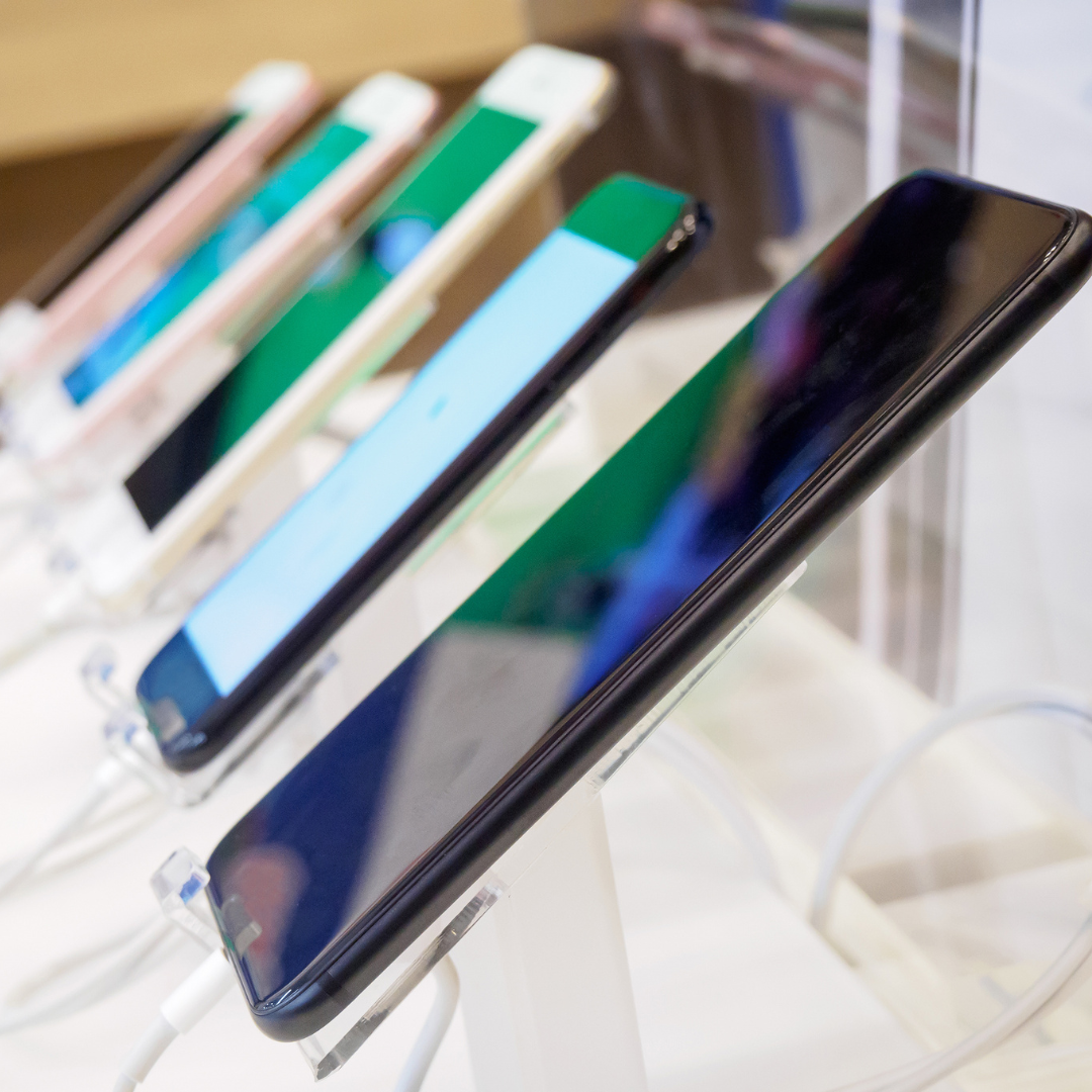 A row of cell phones on display in a store setting.
