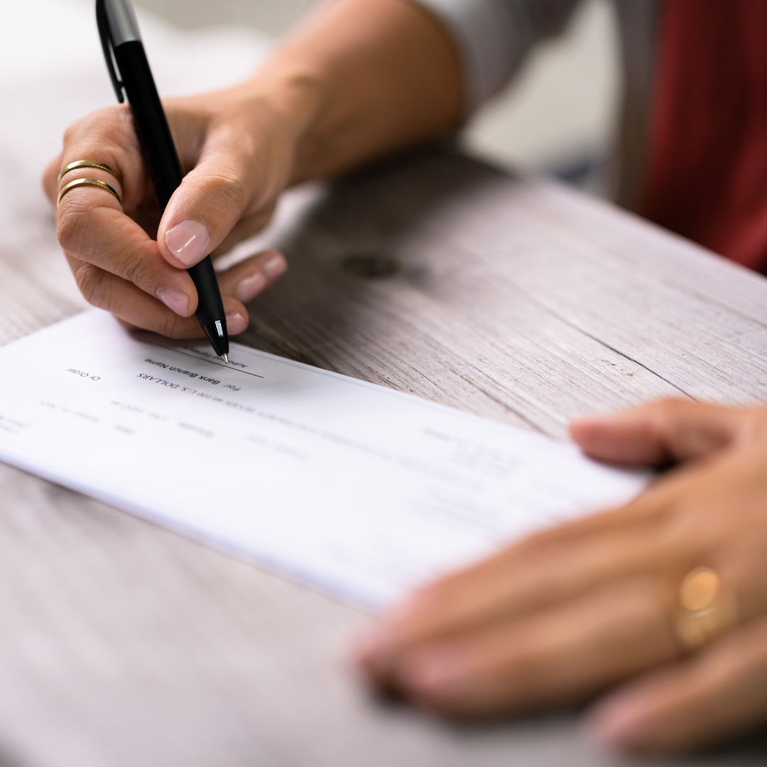 A hand filling out a check