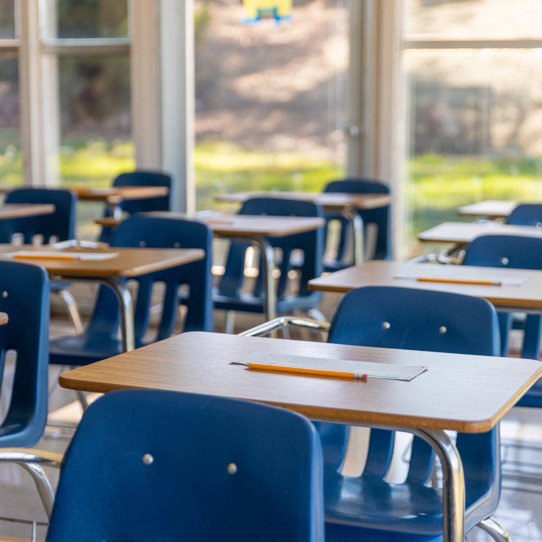 Wooden desks with blue chairs inside a classoom.