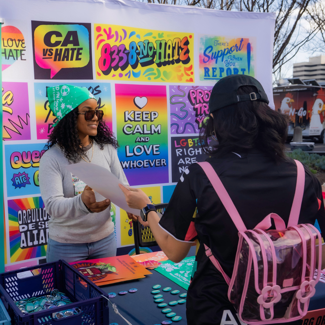 Staff share California Versus Hate resources to soccer fans at an Oakland Roots game.