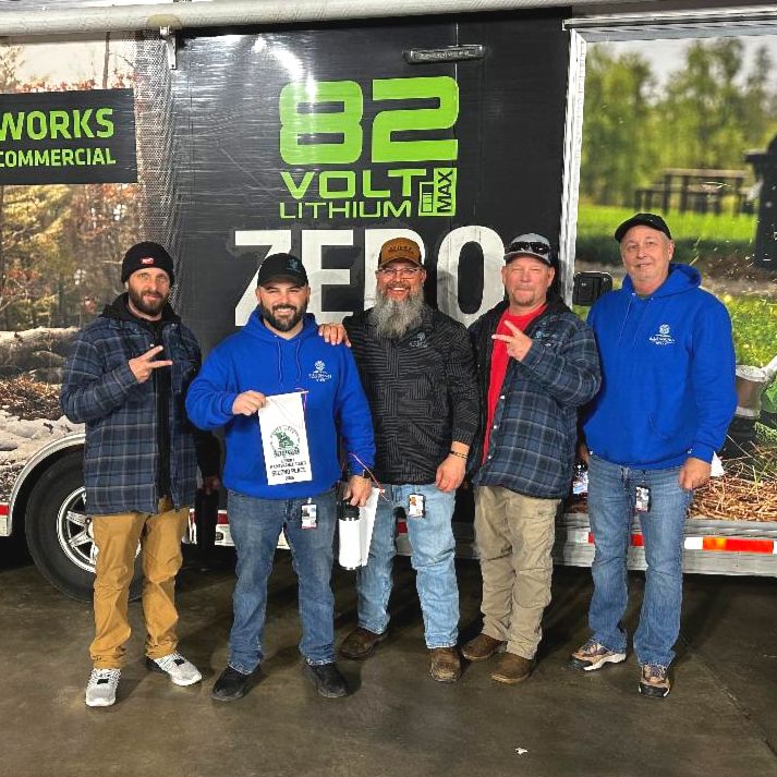 Five parks maintenance team members smile for a photo with a prize banner at the regional maintenance rodeo.