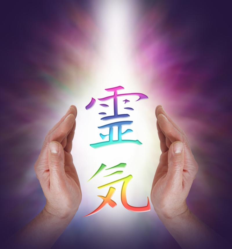Reiki Kanji Symbol floating between Male healer s hands with a shaft of white light behind on a dark background