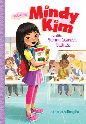 Cover of the book Mindy Kim and the Yummy Seaweed Business by Lyla Lee illustrated by Dung Ho. The artwork shows a smiling girl with long black hair wearing a yellow shirt and pink pants holding a box of seaweed snacks. She has a backpack and is standing in a classroom where other children are seated at desks. The title is in bold pink and purple lettering at the top.
