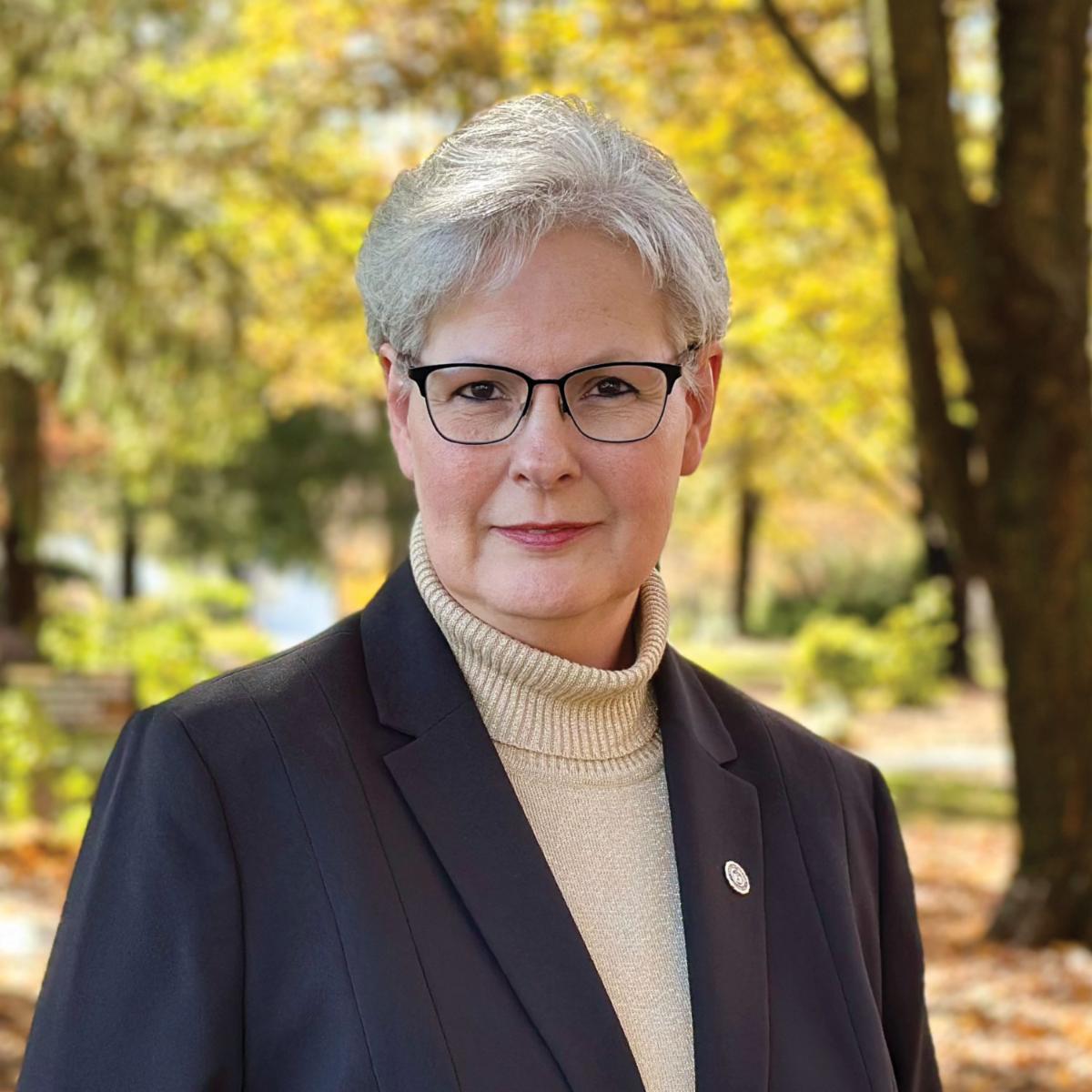 Chris Watters standing outside on campus with fall colors on the tress behind