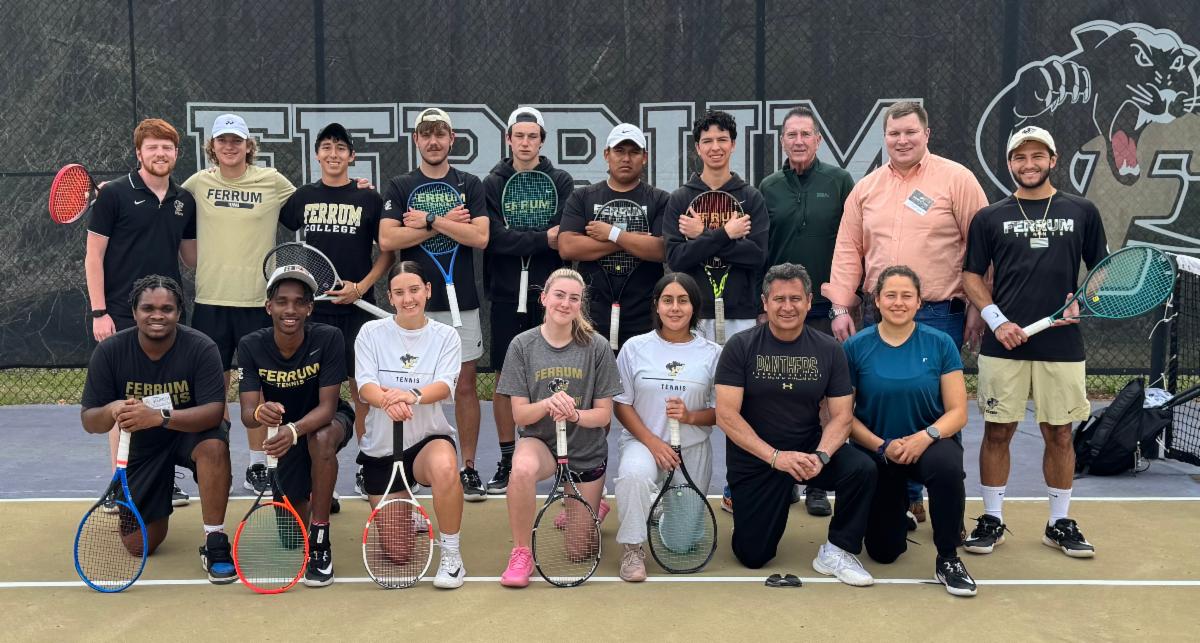 A group of men and women pose together with their tennis rackets on a tennis court with Ferrum and the panther logo behind them