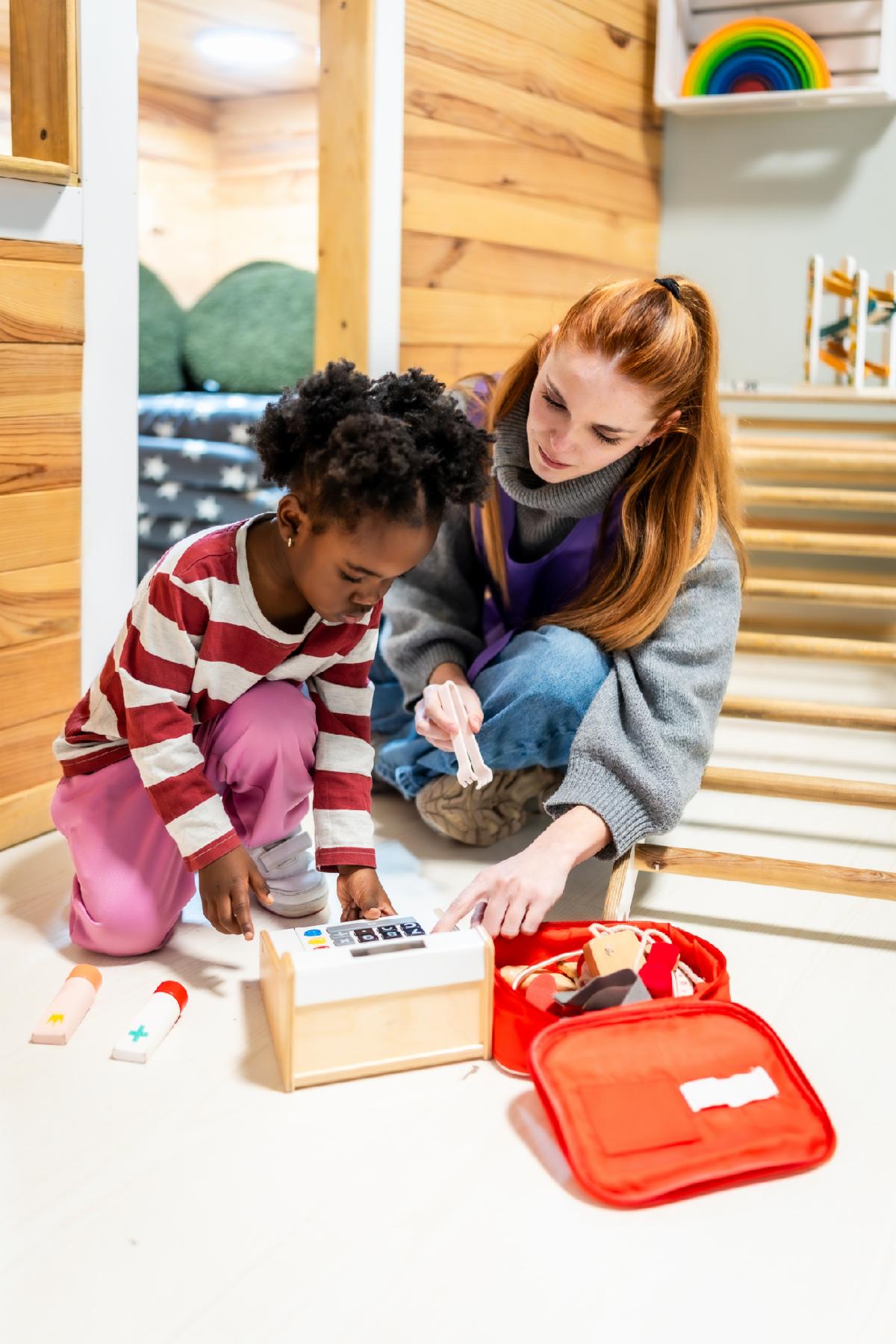 Preschool teacher and young african american child engaging in imaginative role-play with a toy doctor kit and cash register fostering early childhood development and learning
