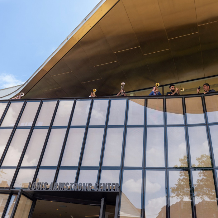 outside photo of Armstrong center with trumpet players playing on balcony