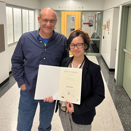 Sujen WuWu in hallway holding her certificate