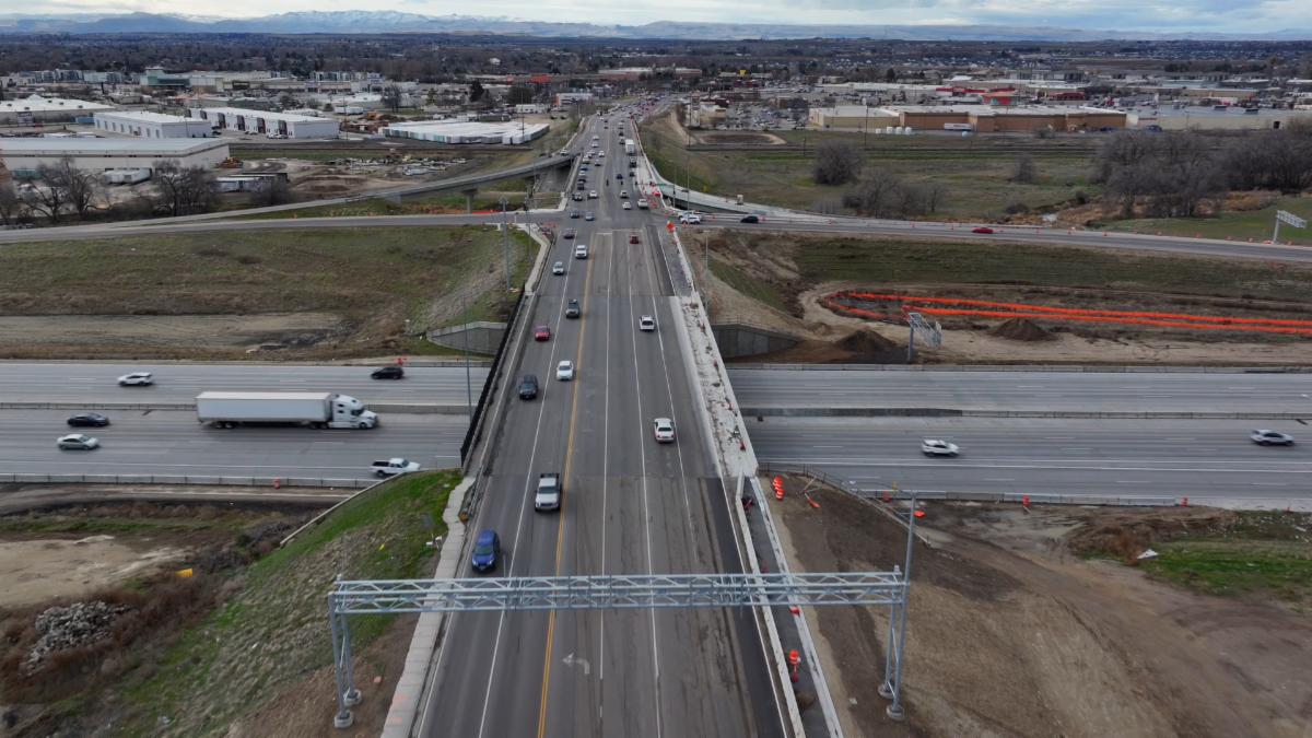 Karcher Rd facing south with I-84 crossing below. Cars are on the roadway and buildings are in the background.