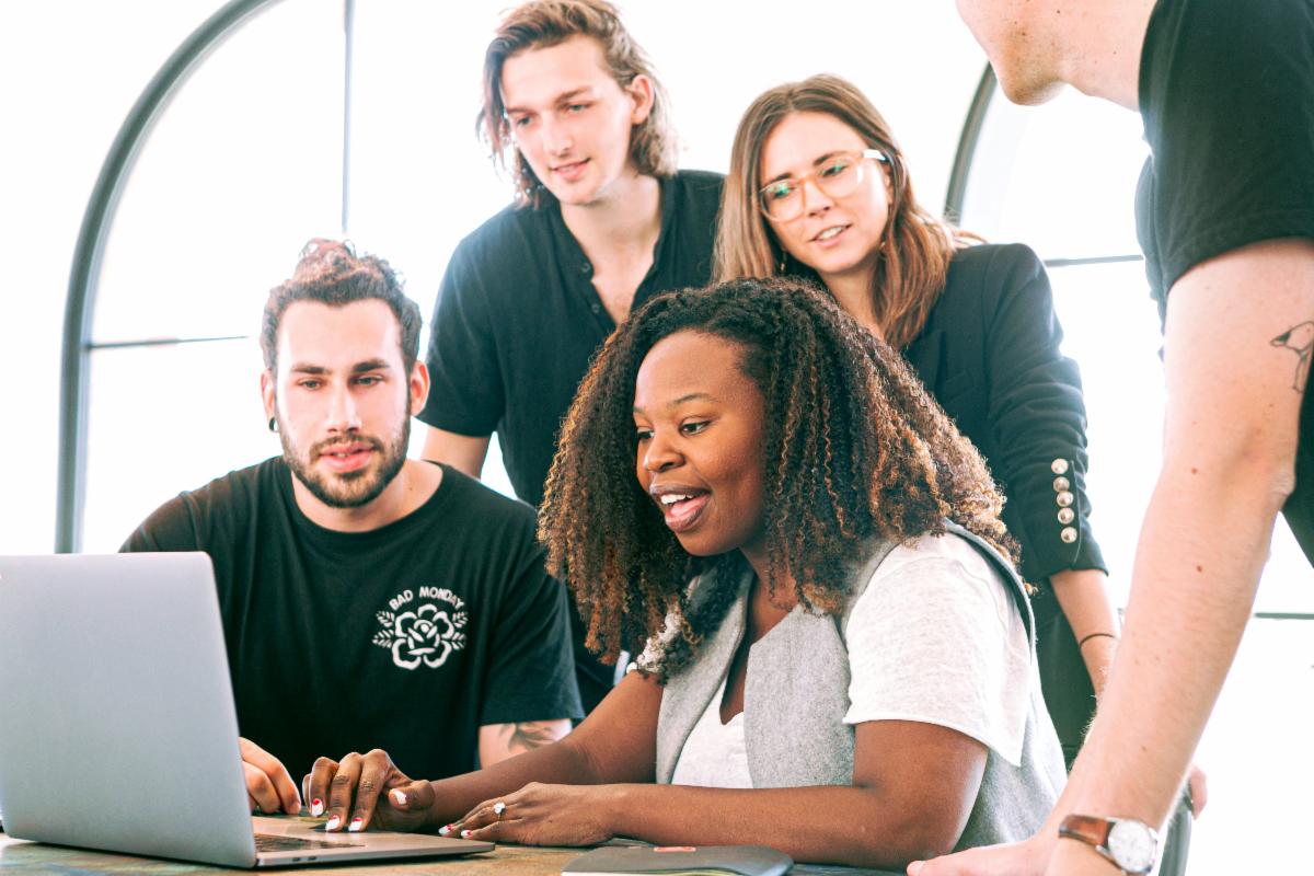diverse people around a laptop for a webinar or workshop