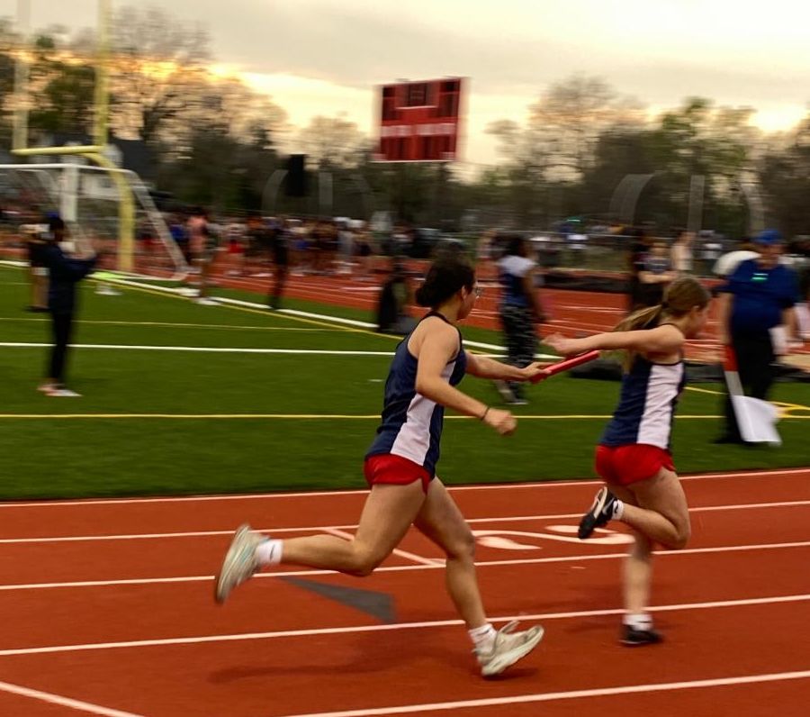 Two AL students running relay on a track.