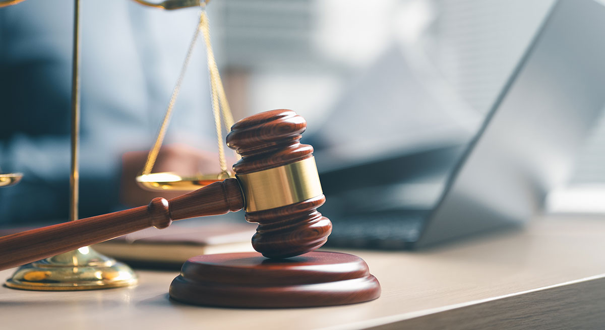 Photo of a judge's gavel next to a laptop computer