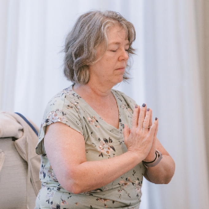 Photo of WM patient seated with eyes closed and hands at heart center during a wellness class