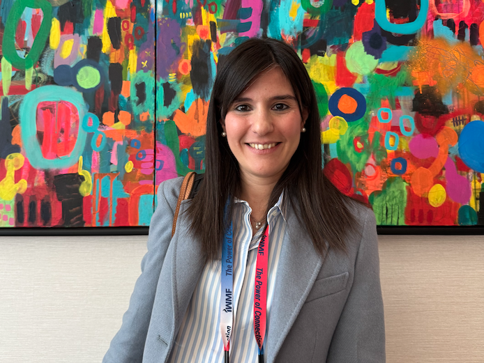 Pic of Dr. Patrizia Mondello in front of a colorful abstract painting, smiling