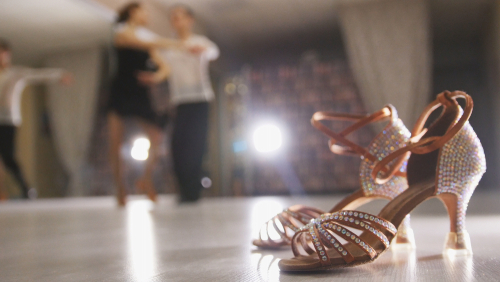 Blurred professional man and woman dancing Latin dance in costumes in the Studio_ ballroom shoes in the foreground