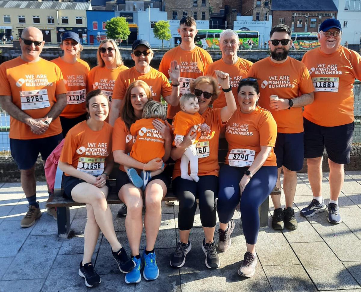 A large group of people wearing orange Fighting Blindness t-shirts. They are all participants and supporters in attendance at the Cork City Marathon