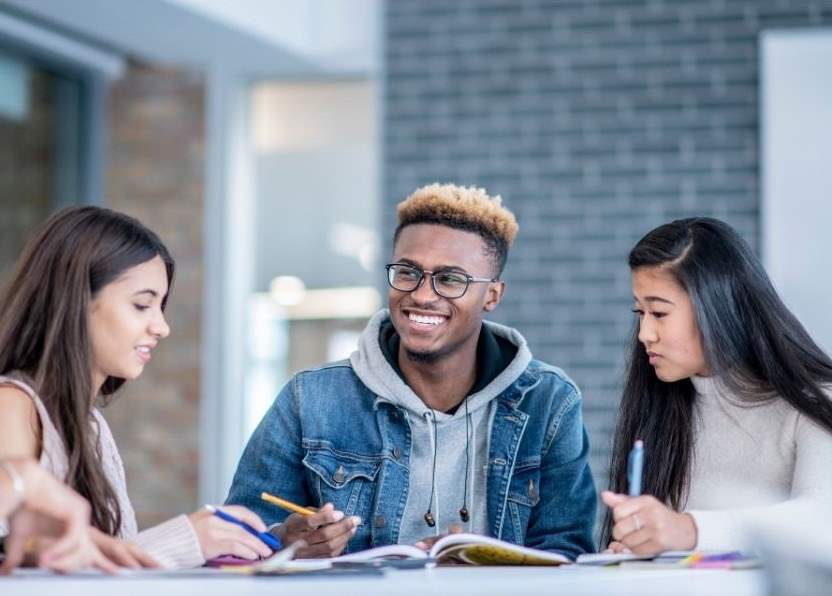 three teens working in a group setting.