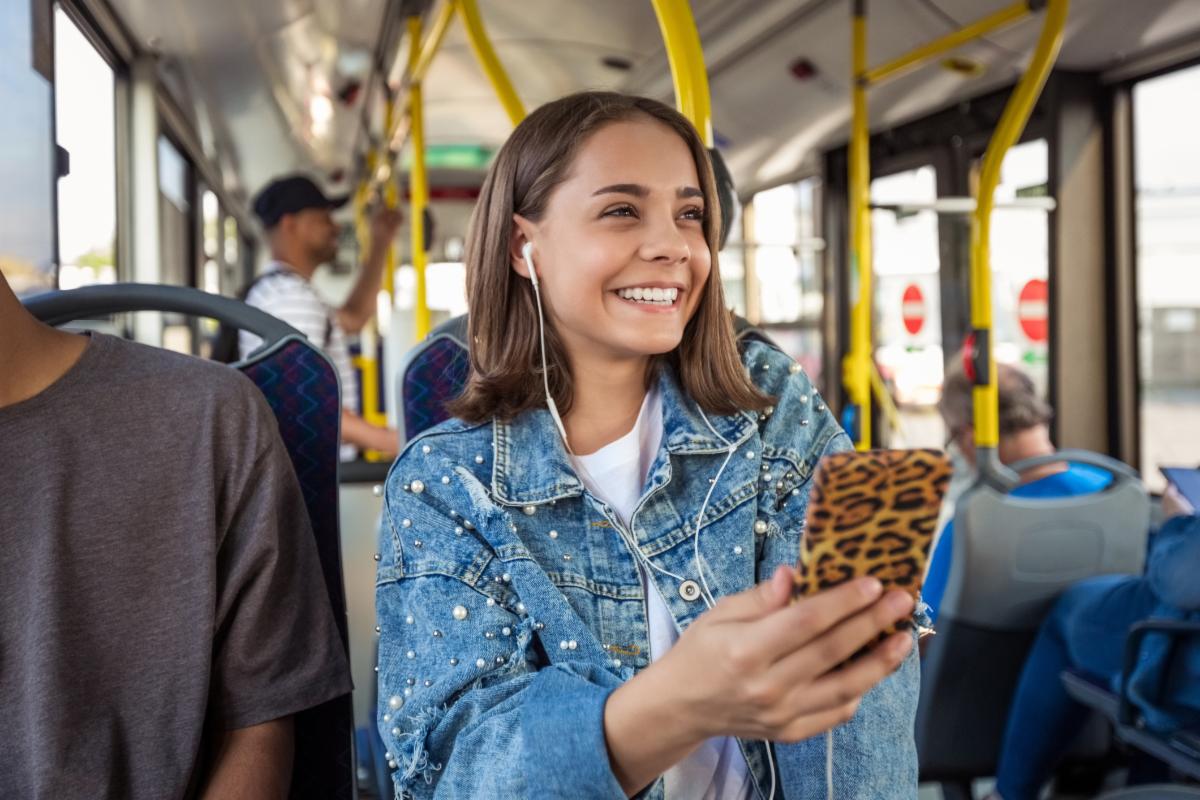Teen riding a public bus holding a cell phone