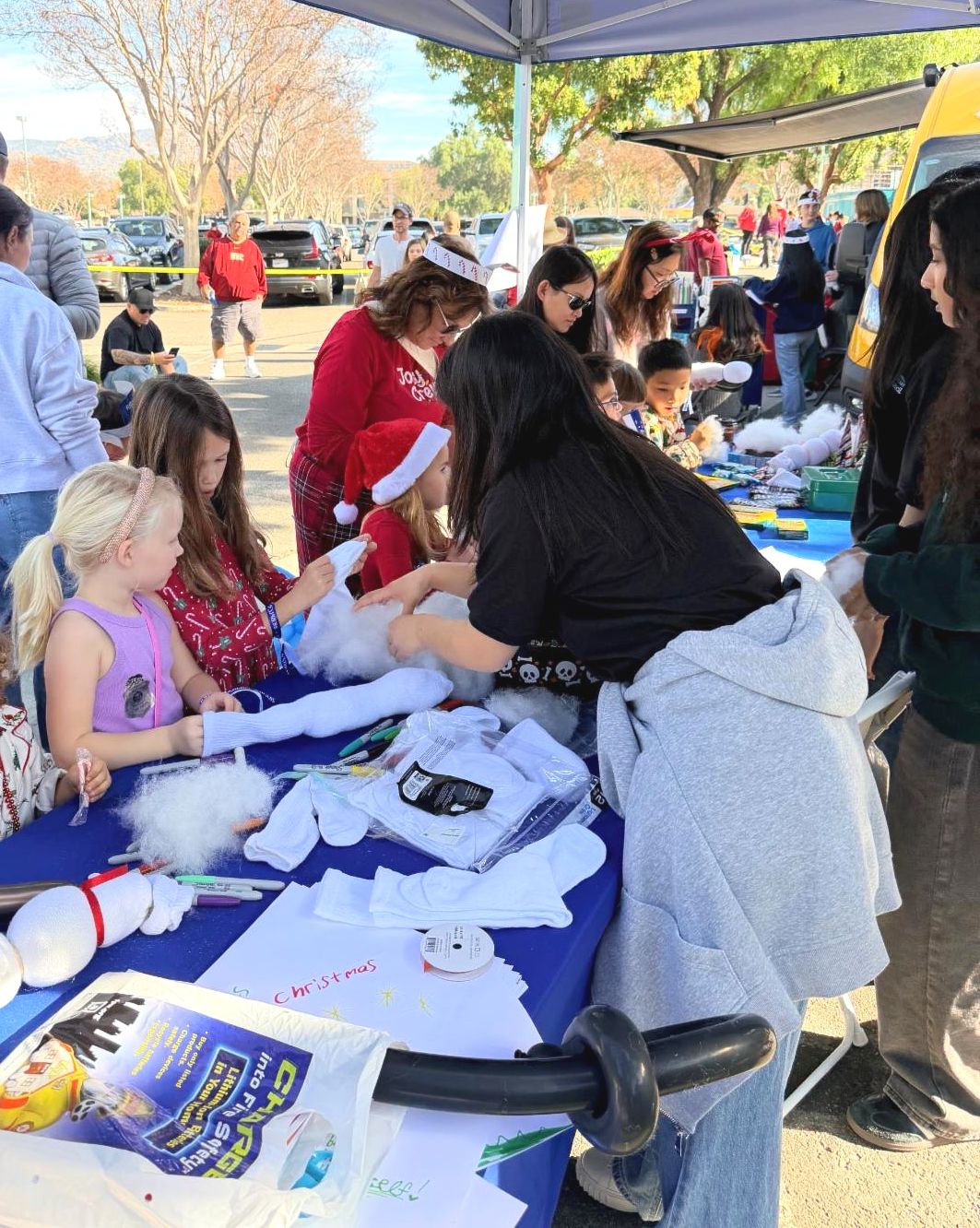 Youth Council members helping two children do a snowman craft at Holiday Express Event booth