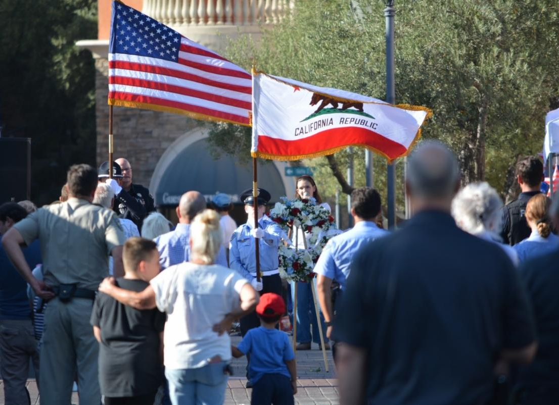 American and California flags with crowd listening to the National Anthem