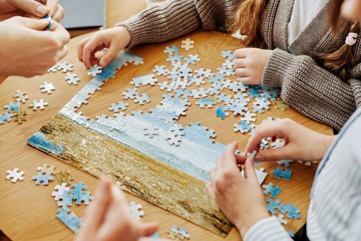 three people putting together a puzzle