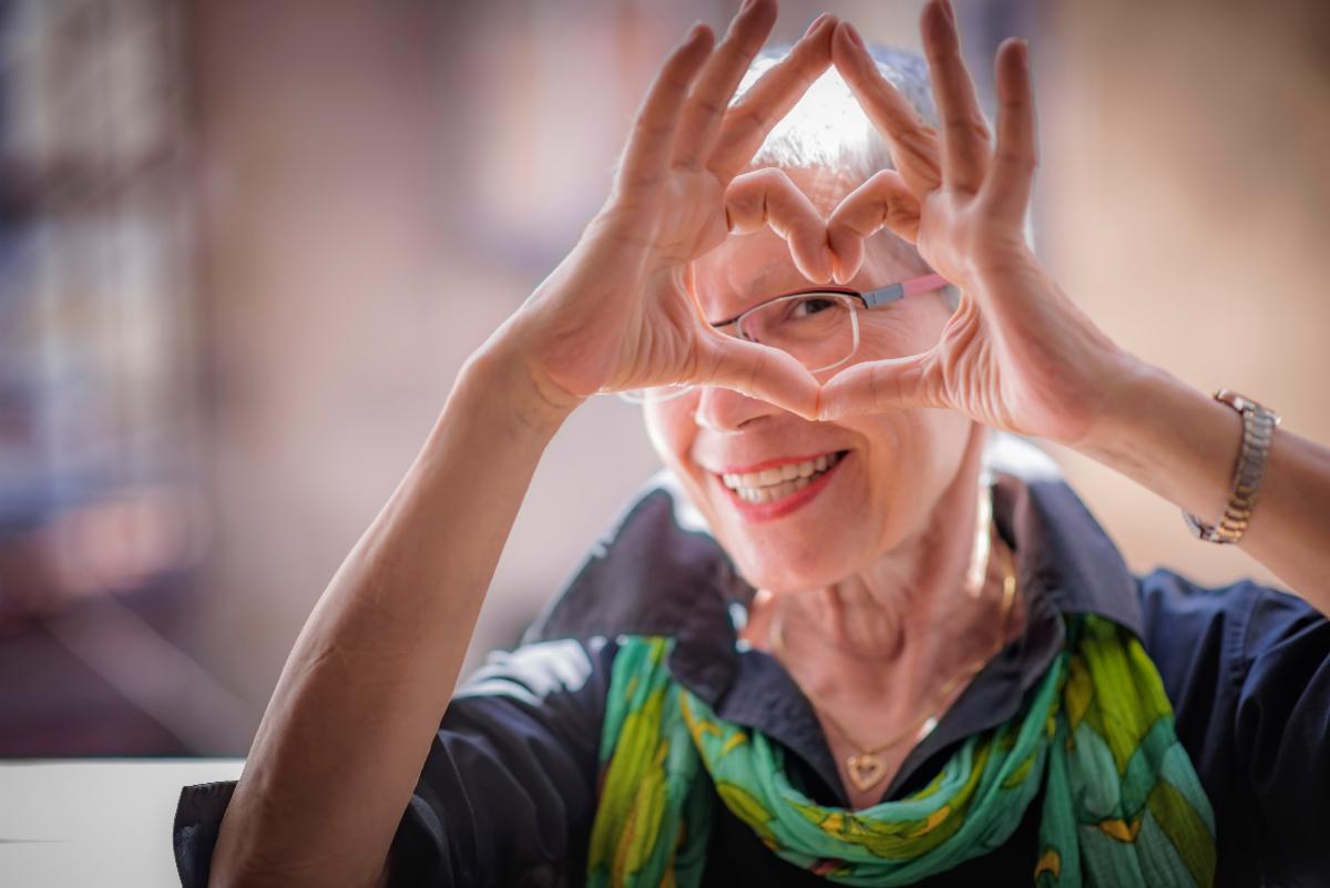 Senior woman making a heart symbol with her hands.