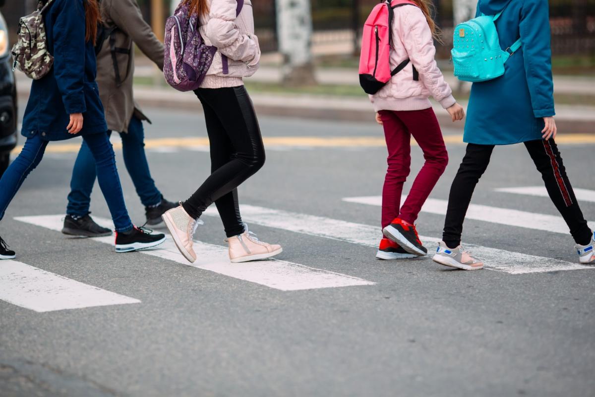 Children walking across a crosswalk to get to school.