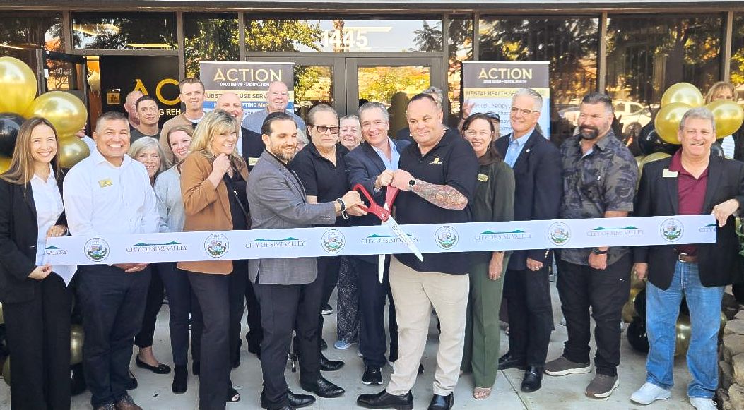 Large group cutting a ribbon in front of newly opened Action Drug Rehab Center