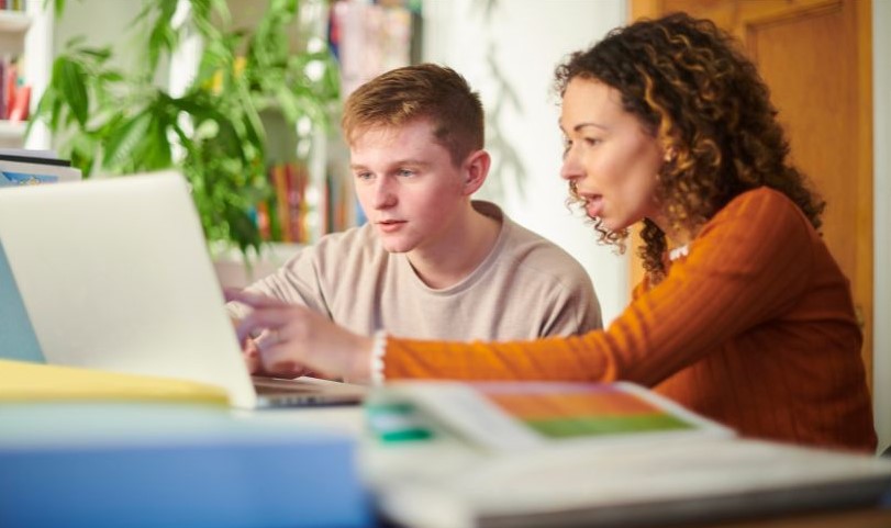 Young student and adult tutor sitting at a desk