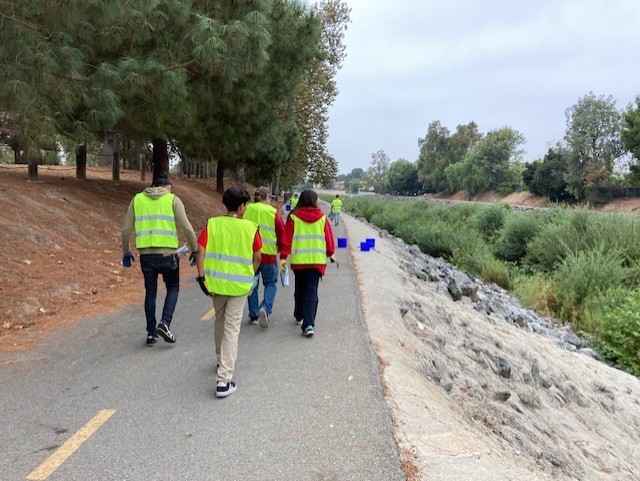Photo of volunteers wearing yellow vests walking away from camera along the Arroyo Simi walking path