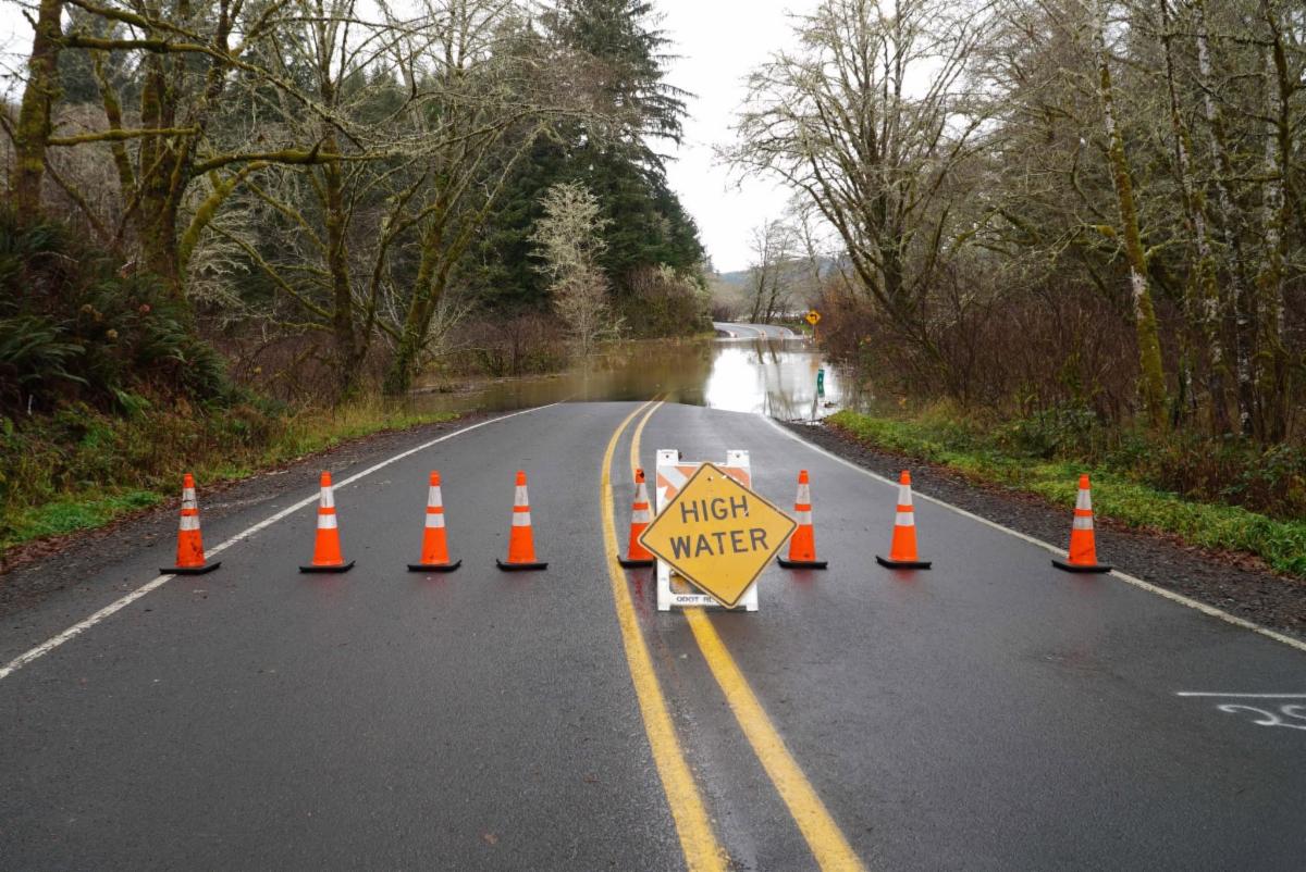 Flooded road blocked off with cones and a sign