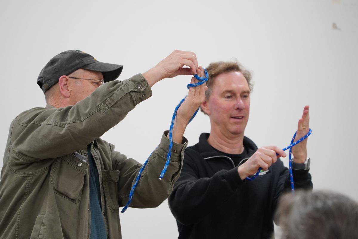 Two people demonstrate tying or securing a blue cord during an emergency preparedness training session.