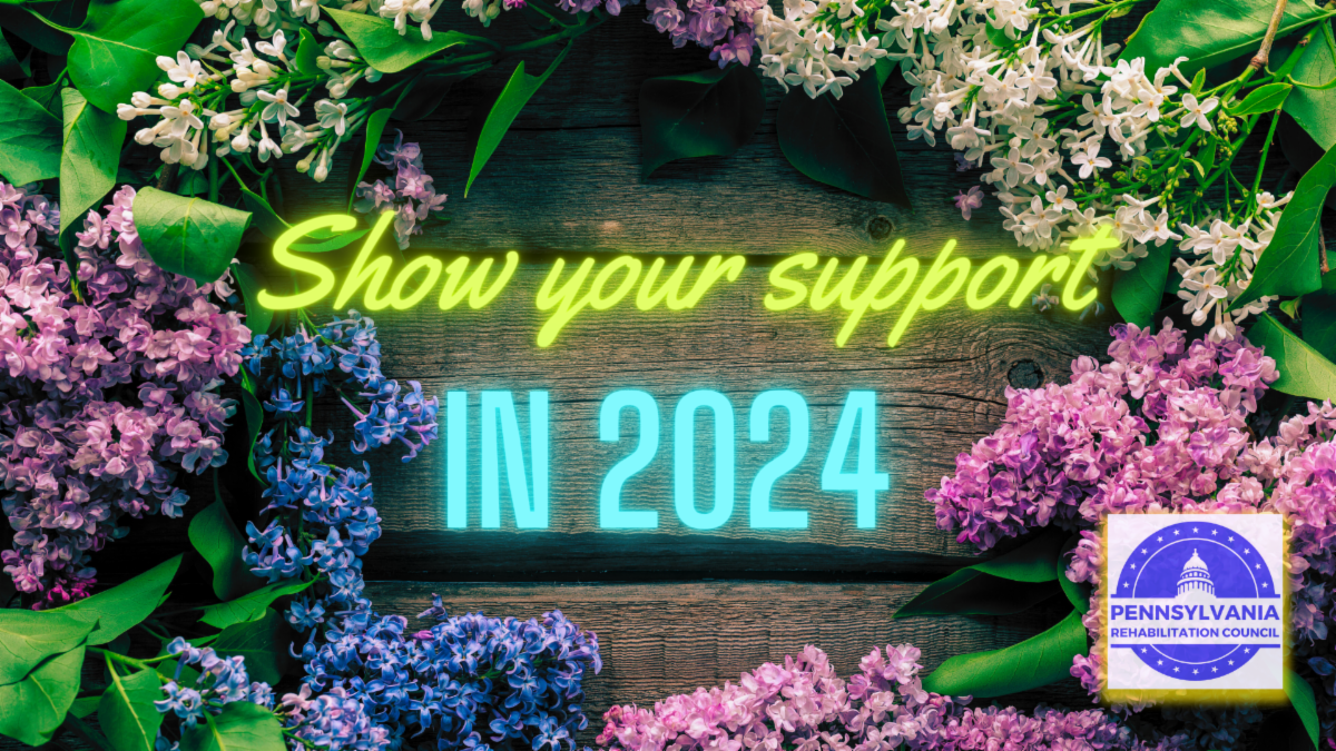 The text Show your support in 2024 centered within a circle of purple and blue flowers sitting on a wooden table