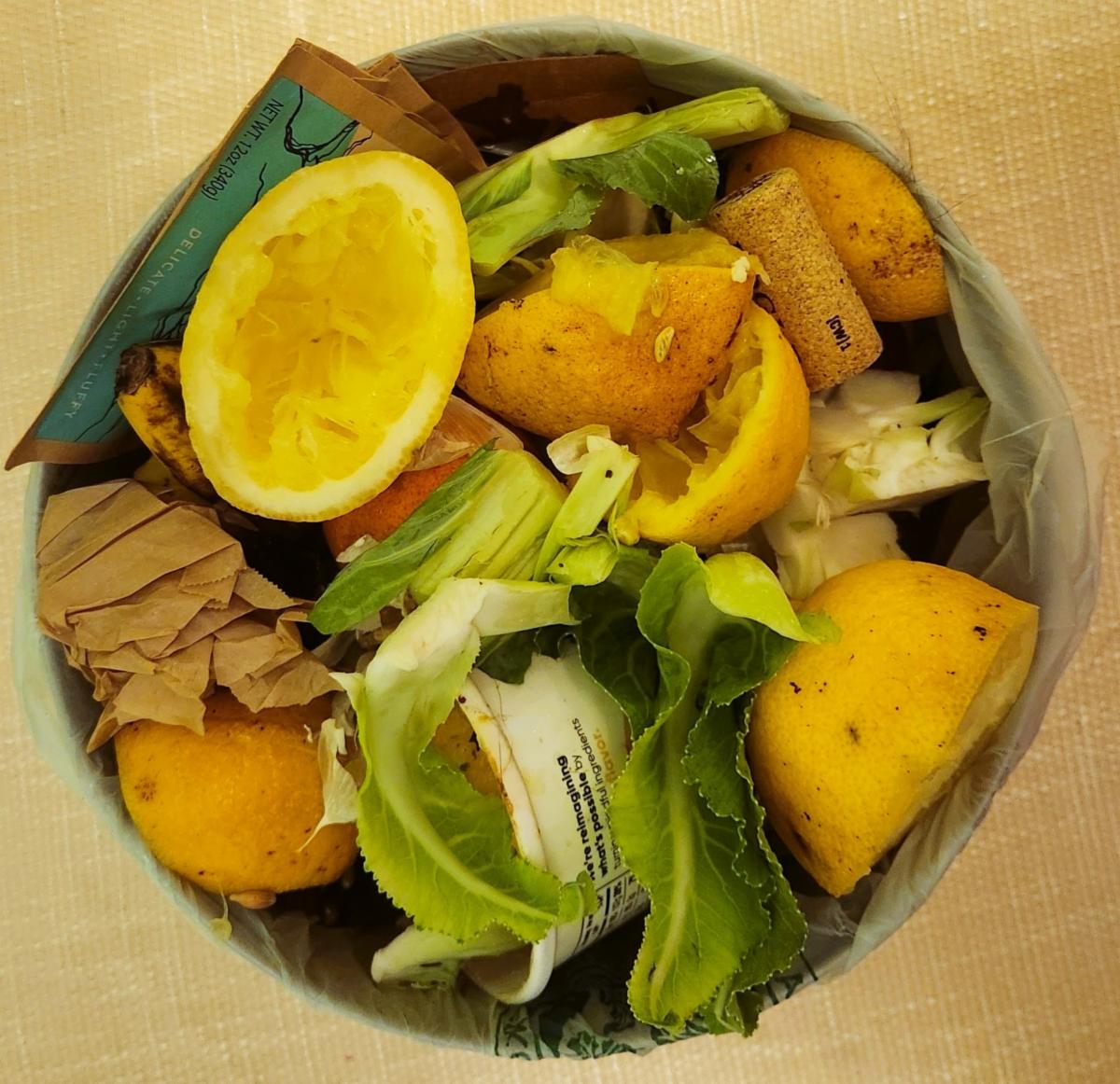 Compostable materials like food scraps, a cork, and other items in a bowl on a counter.