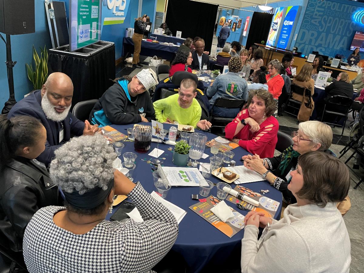 Adults and youth sit around a table and have a discussion