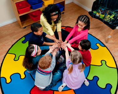 young children and teacher in a circle touching hands