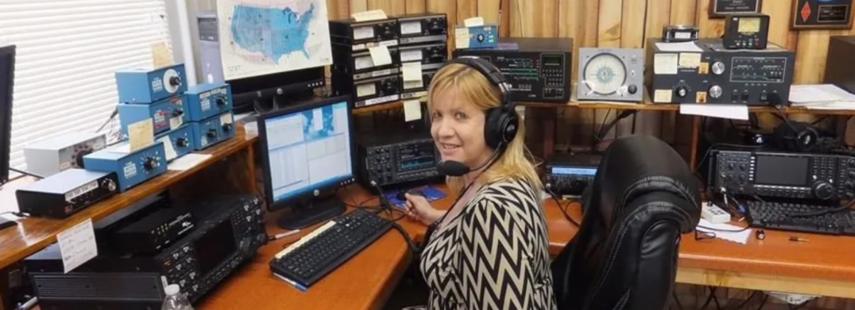 Ham radio operator wearing headsets in front of radio equipment