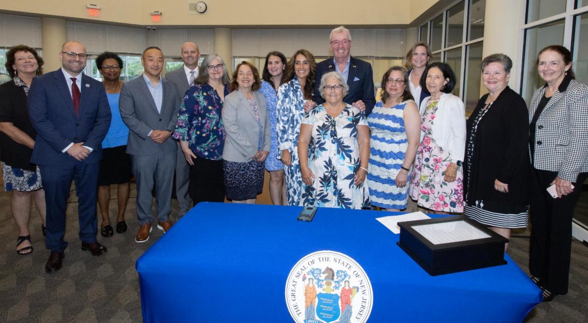 Imagen que muestra a personas en la firma del proyecto de ley de alfabetización, incluido el gobernador de Nueva Jersey, Phil Murphy, la directora de políticas de SPAN, Peg Kinsell, y la líder de la mayoría del Senado de Nueva Jersey, Teresa Ruiz.