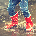 Botas de lluvia infantiles salpicando en un charco