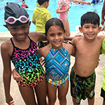 Ni_os sonrientes en traje de ba_o alrededor de una piscina