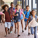 Ni_os felices corriendo por los pasillos de una escuela.
