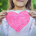 Jovencita sosteniendo un coraz_n del amor en cartulina.
