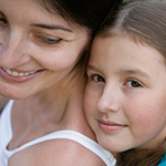 Madre sonriente siendo abrazada por su joven hija