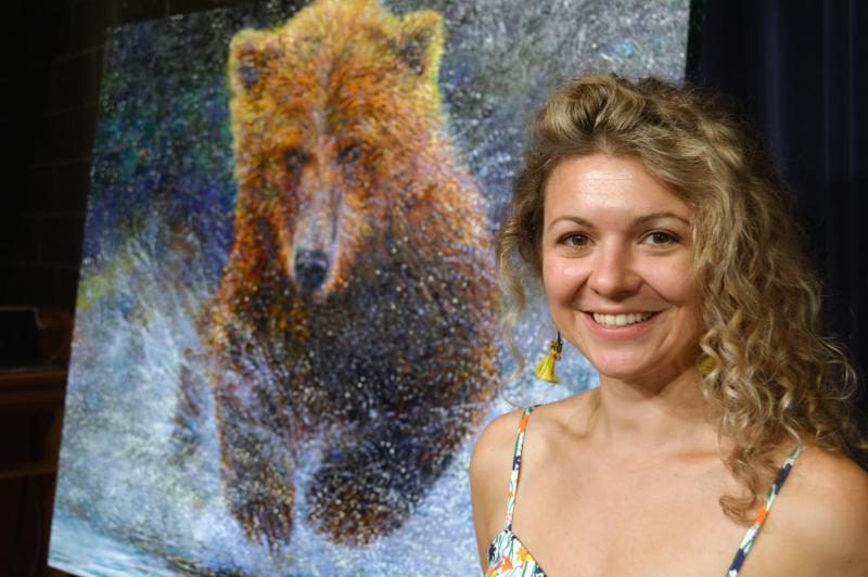 Iris Scott poses with her new painting of a grizzly